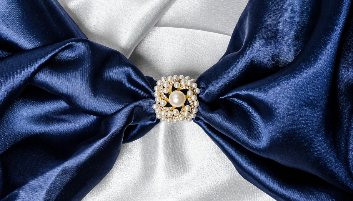Broche en perles posée sur un ruban de satin bleu nuit